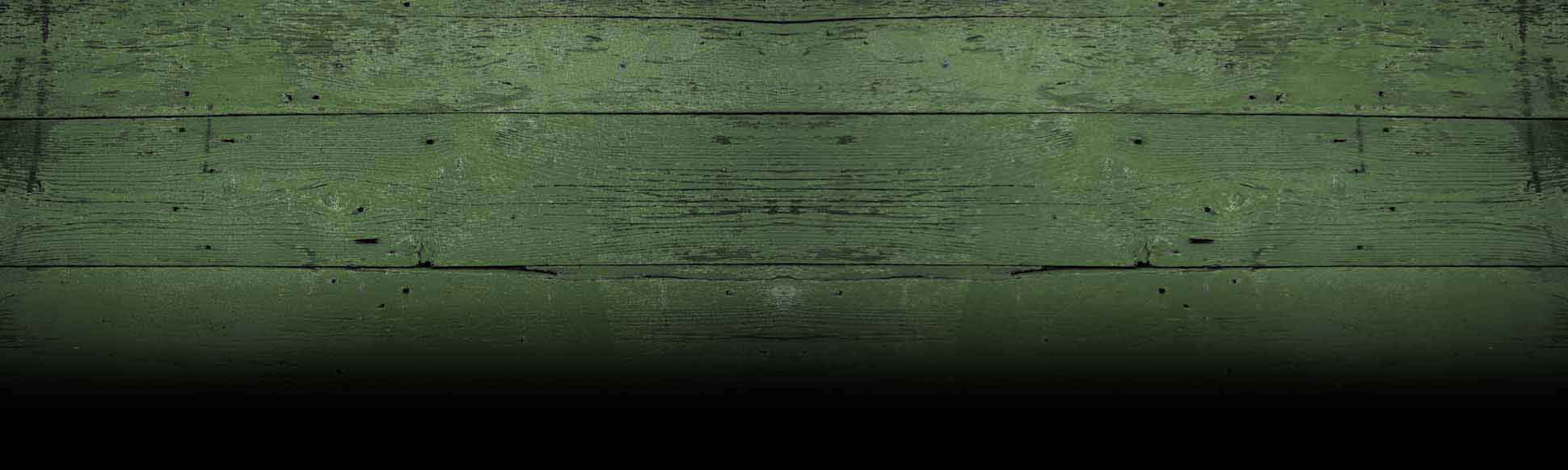 Weathered green painted wooden planks fading to black, creating a textured backdrop with a grounded, organic feel.
